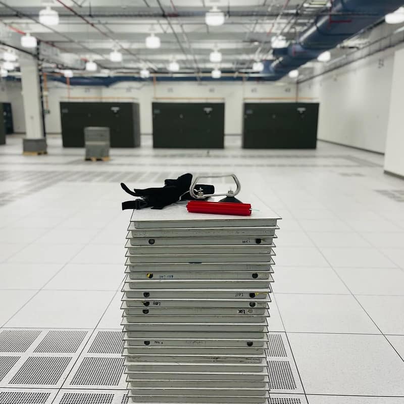 Stack of lifted raised-floor panels with a panel lifter in a cleared data hall